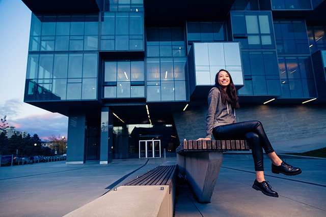 Student sitting outside glass building